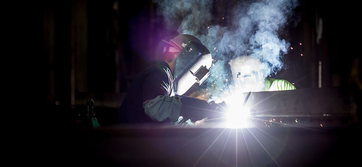 A person welding in the dark with smoke coming from it.