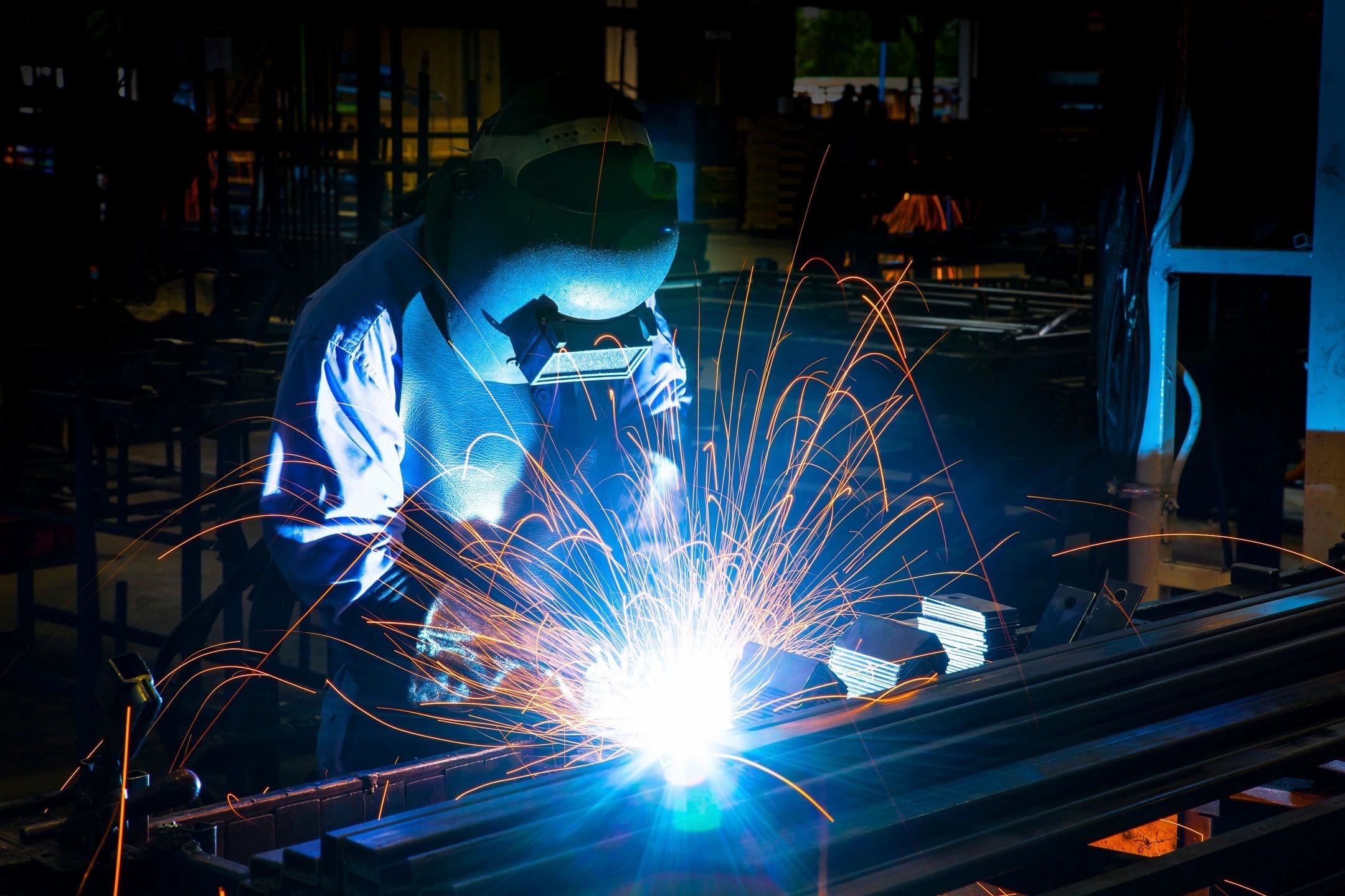 A person welding metal with sparks flying.