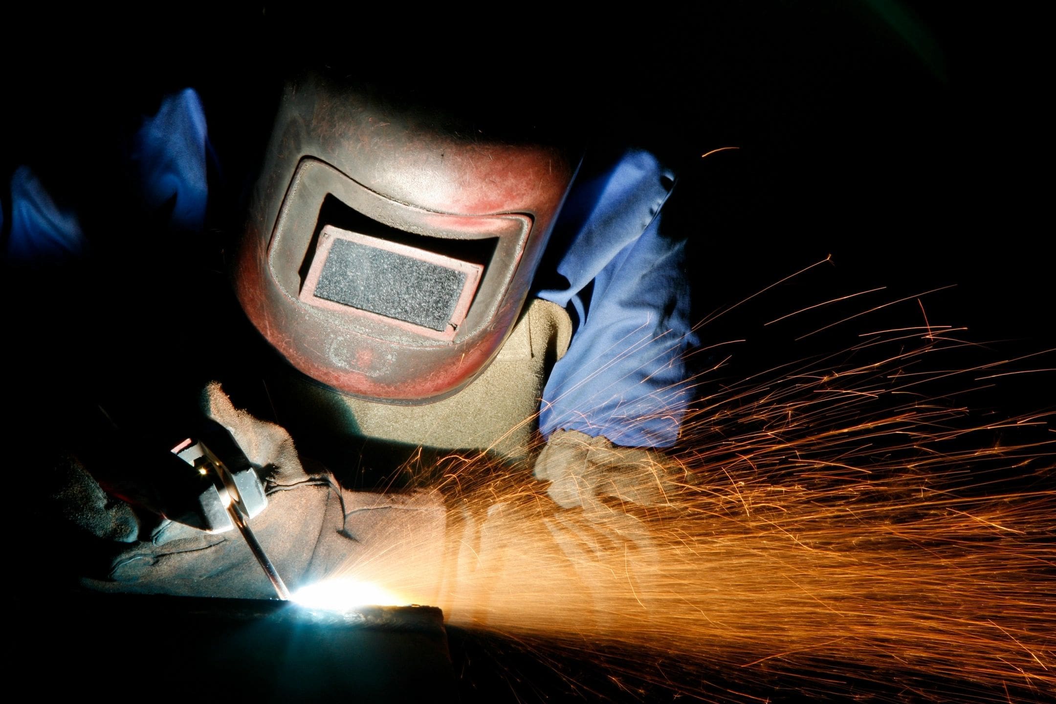 A person welding with an electronic meter on their face.