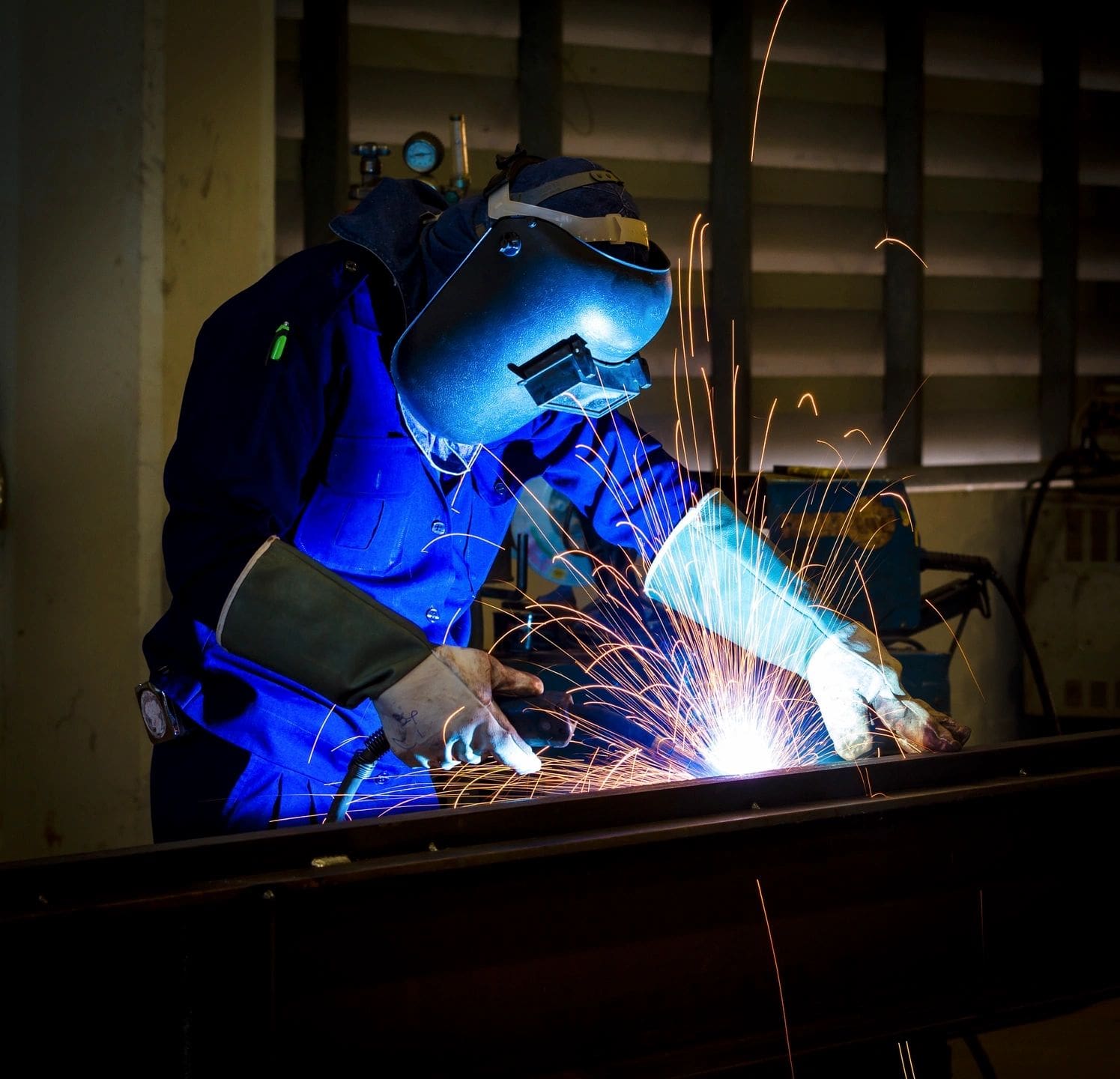 A person welding in the dark with blue lights.