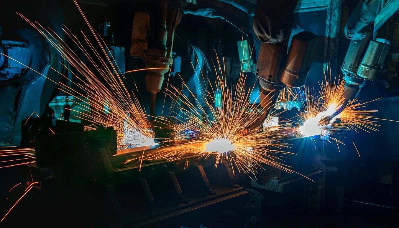 A group of people welding in an industrial setting.