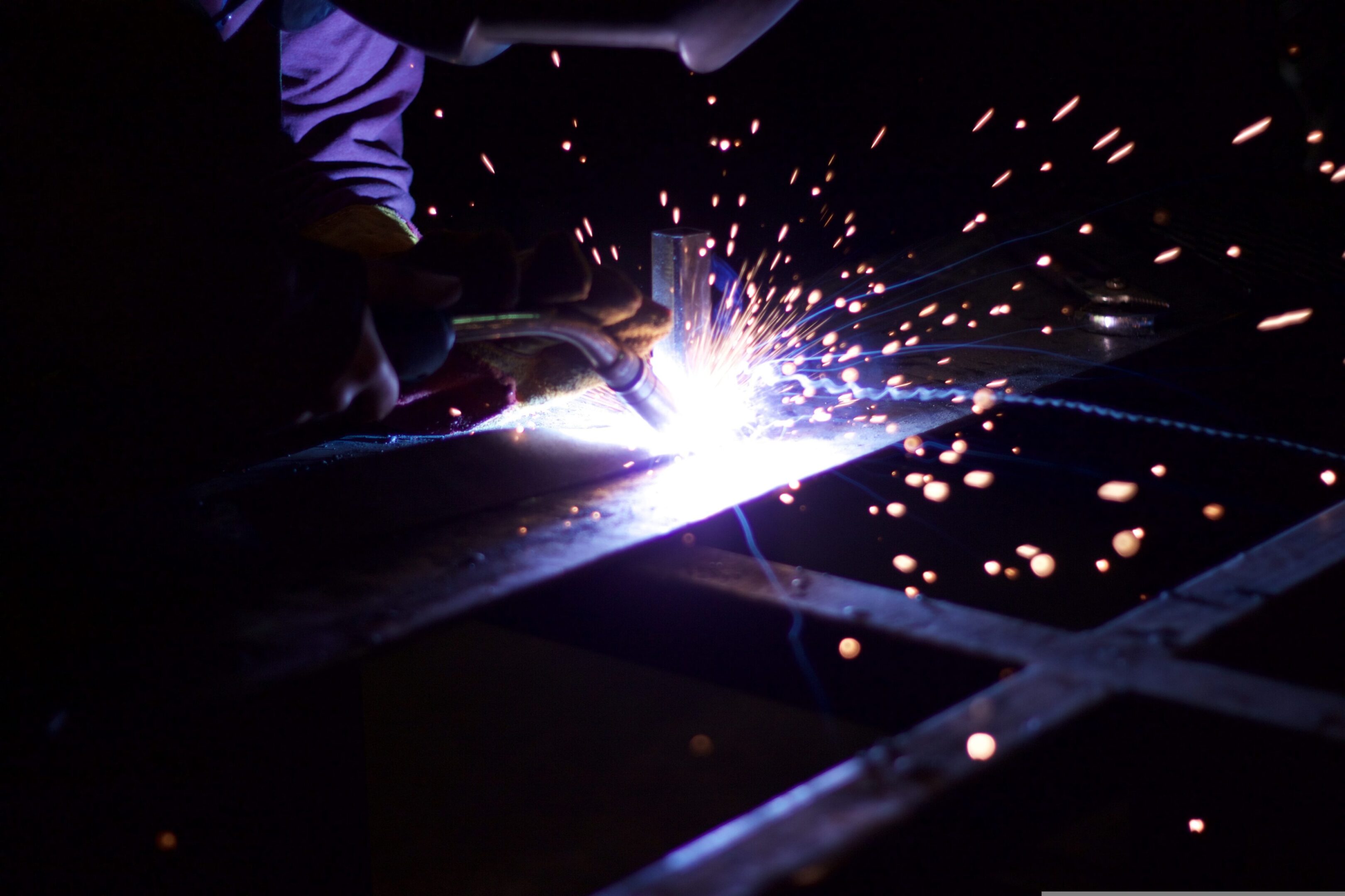 A person welding metal with sparks flying.