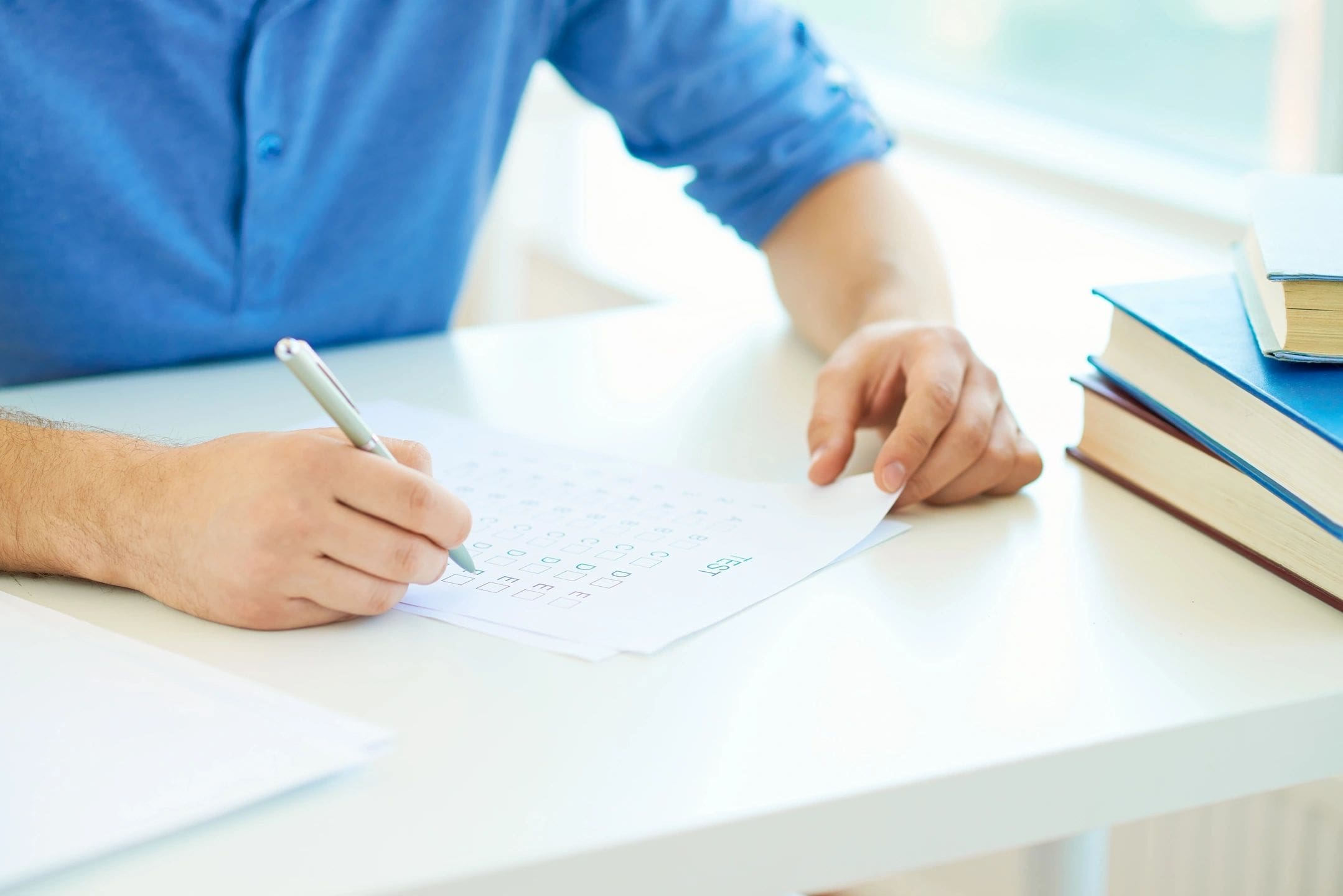 A person writing on paper with pen and pencil.