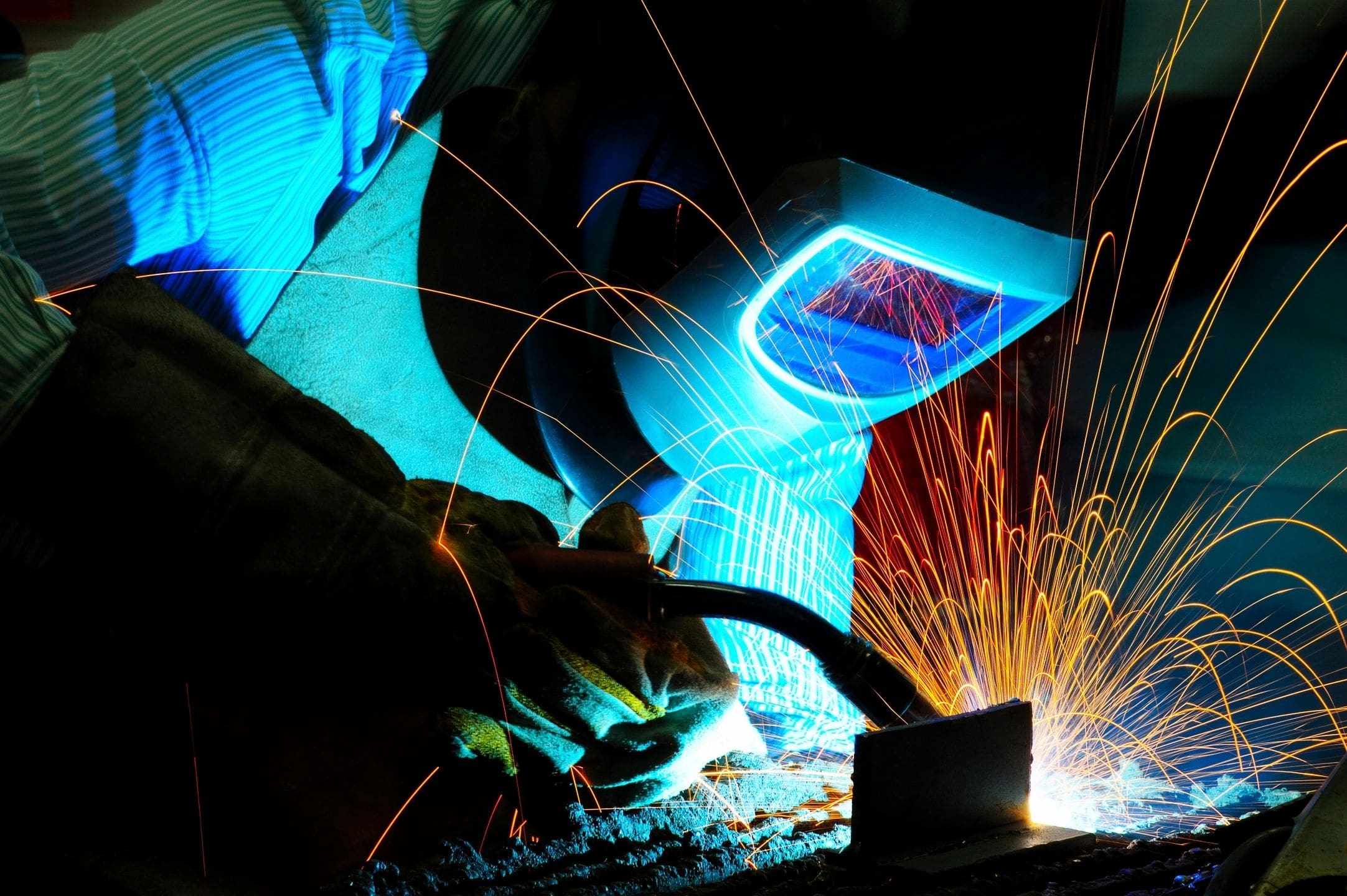 A person welding with blue light shining on them.