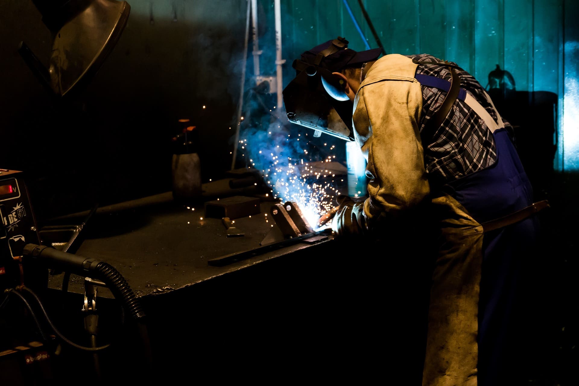 A man welding metal in an industrial setting.